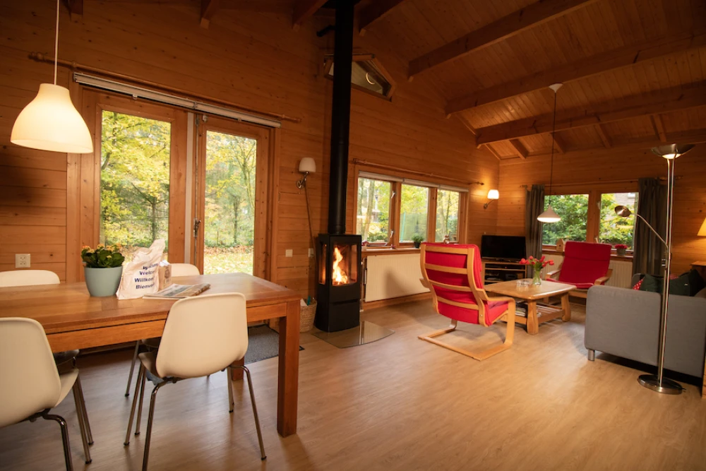 Woonkamer van Het Houten huis – sfeervolle zithoek met houten bungalow, houtkachel, privacy, met uitzicht op het groen.