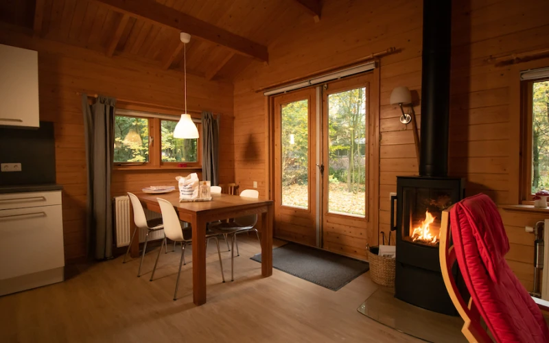 Woonkamer van Het Houten huis – sfeervolle zithoek met houten bungalow, houtkachel, privacy, met uitzicht op het groen.