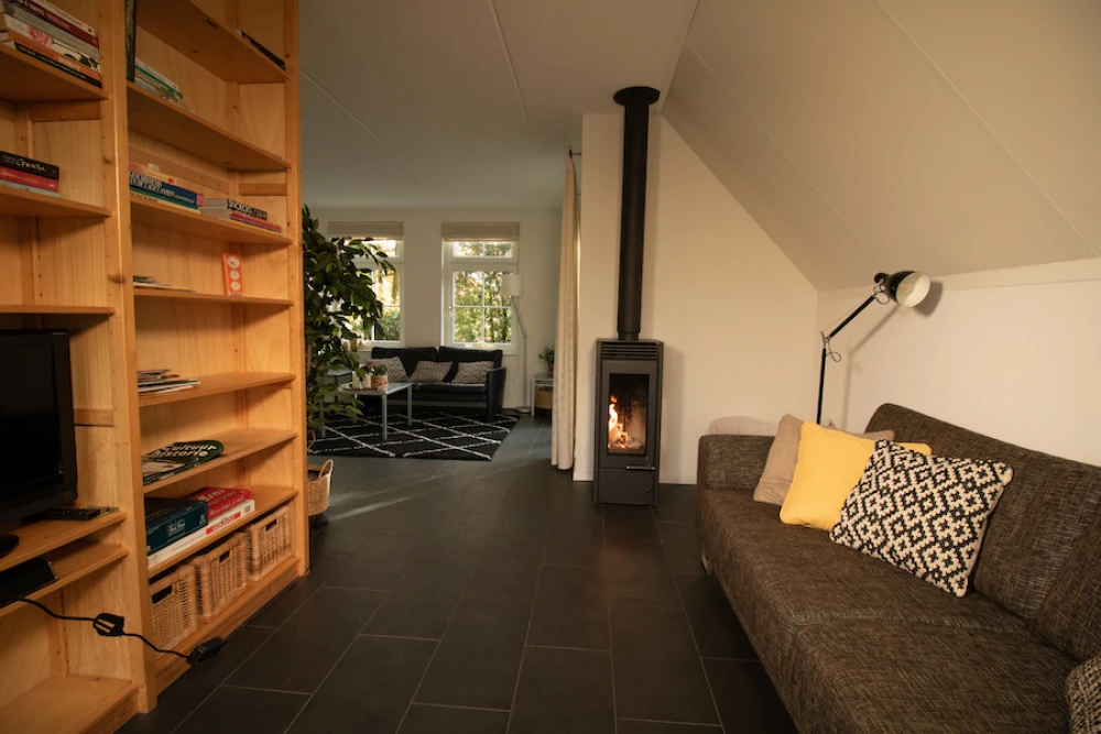Woonkamer van Aurora – sfeervolle zithoek met houtkachel, prachtige ligging, privacy, met uitzicht op het groen.