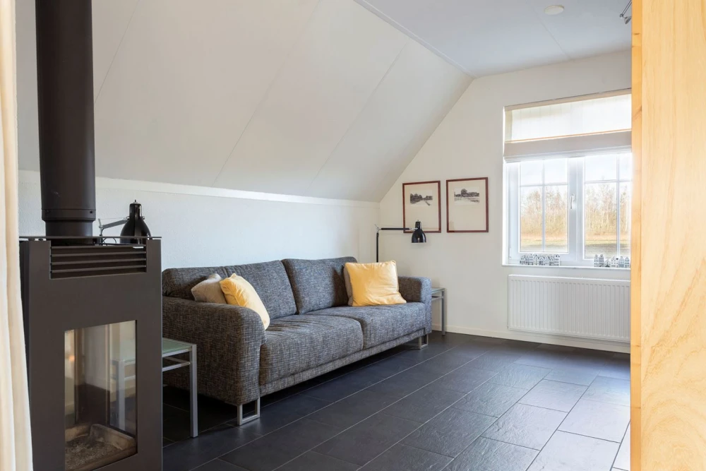 Woonkamer van Aurora – sfeervolle zithoek met houtkachel, prachtige ligging, privacy, met uitzicht op het groen.