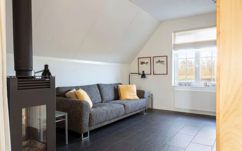 Woonkamer van Aurora – sfeervolle zithoek met houtkachel, prachtige ligging, privacy, met uitzicht op het groen.