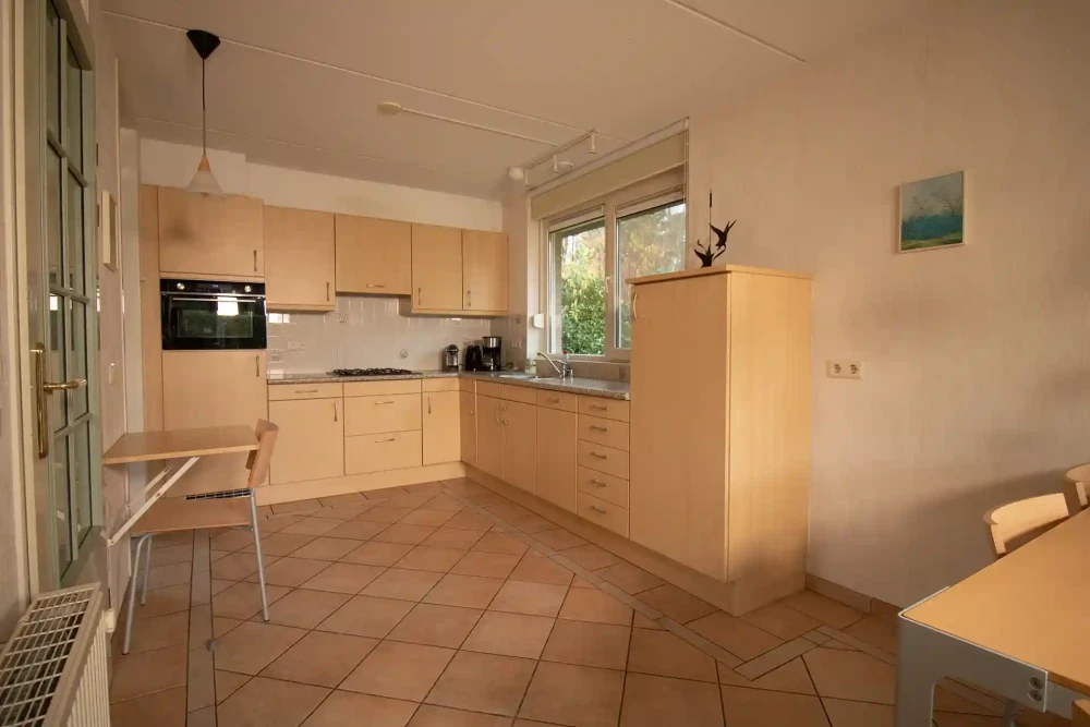 Woonkamer van Hulze – sfeervolle zithoek met houtkachel, met uitzicht op het groen.