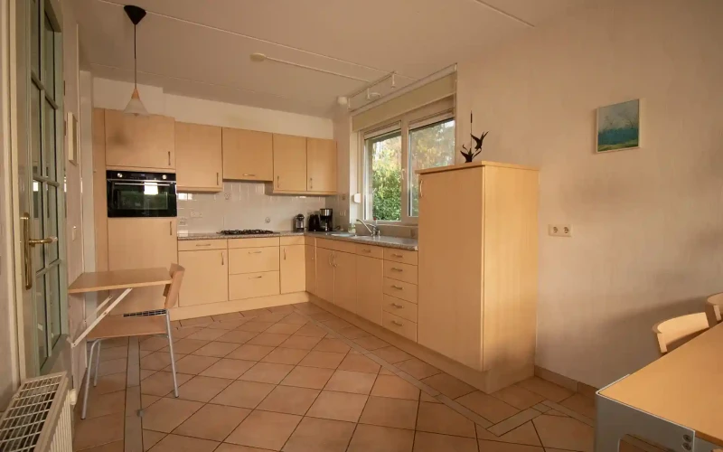 Woonkamer van Hulze – sfeervolle zithoek met houtkachel, met uitzicht op het groen.