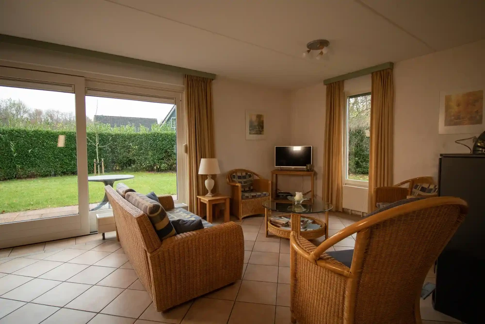 Woonkamer van Hulze – sfeervolle zithoek met houtkachel, met uitzicht op het groen.